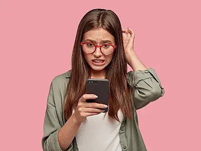 Mulher olha com preocupação para a tela de seu celular.